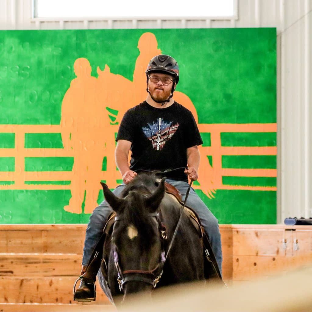 A Main Stay adaptive rider on their horse during a lesson