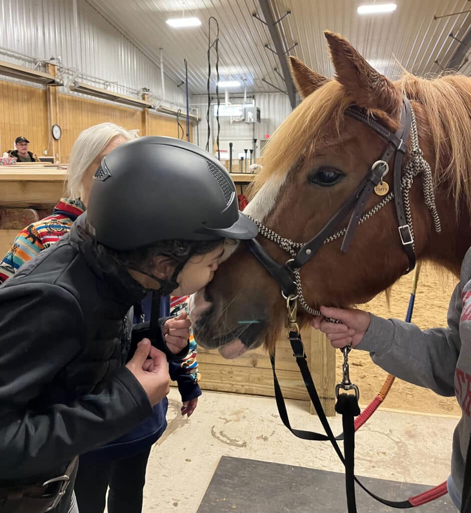 Rider Leah gives adaptive riding horse Harry a kiss on the nose