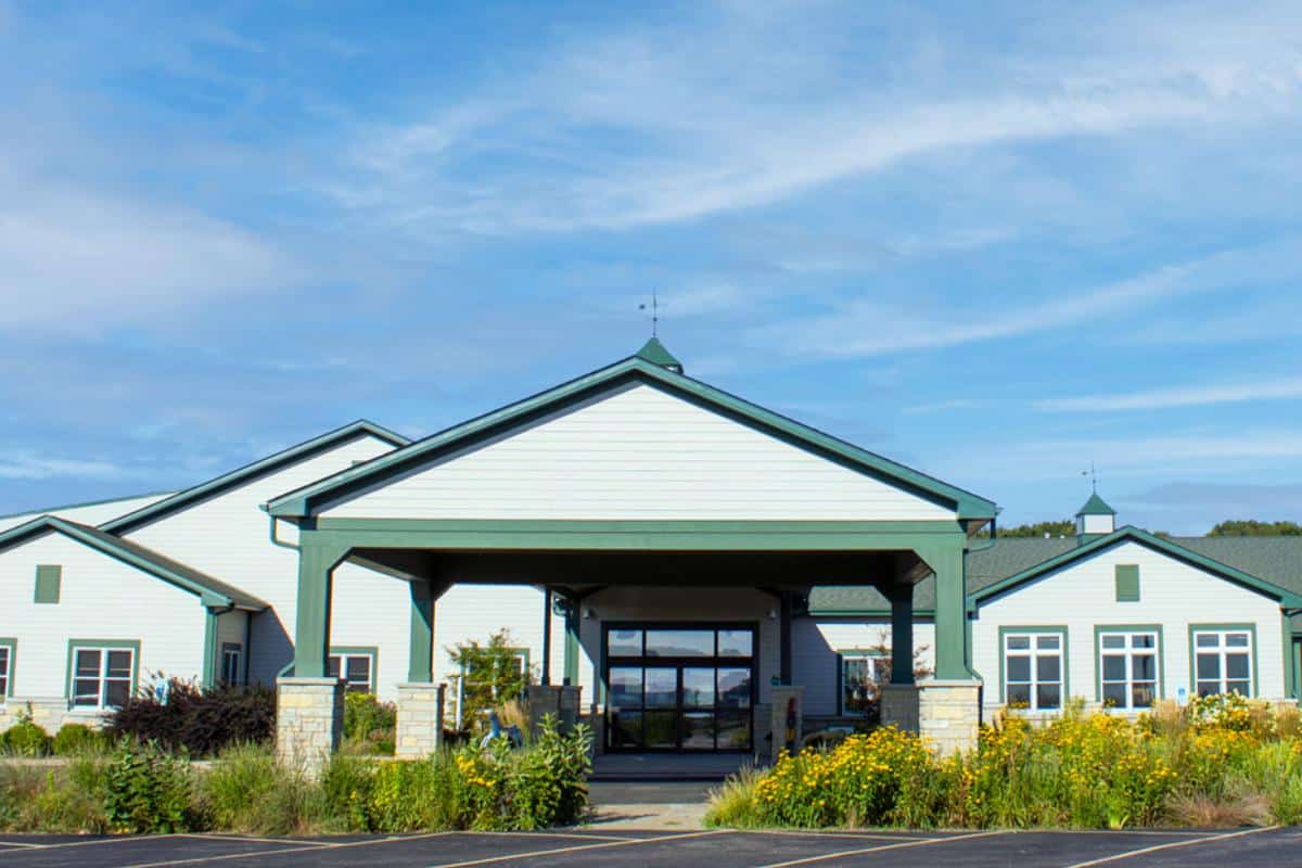 Main Stay’s farmhouse-style facility with green trim, garden beds, and a covered entrance.