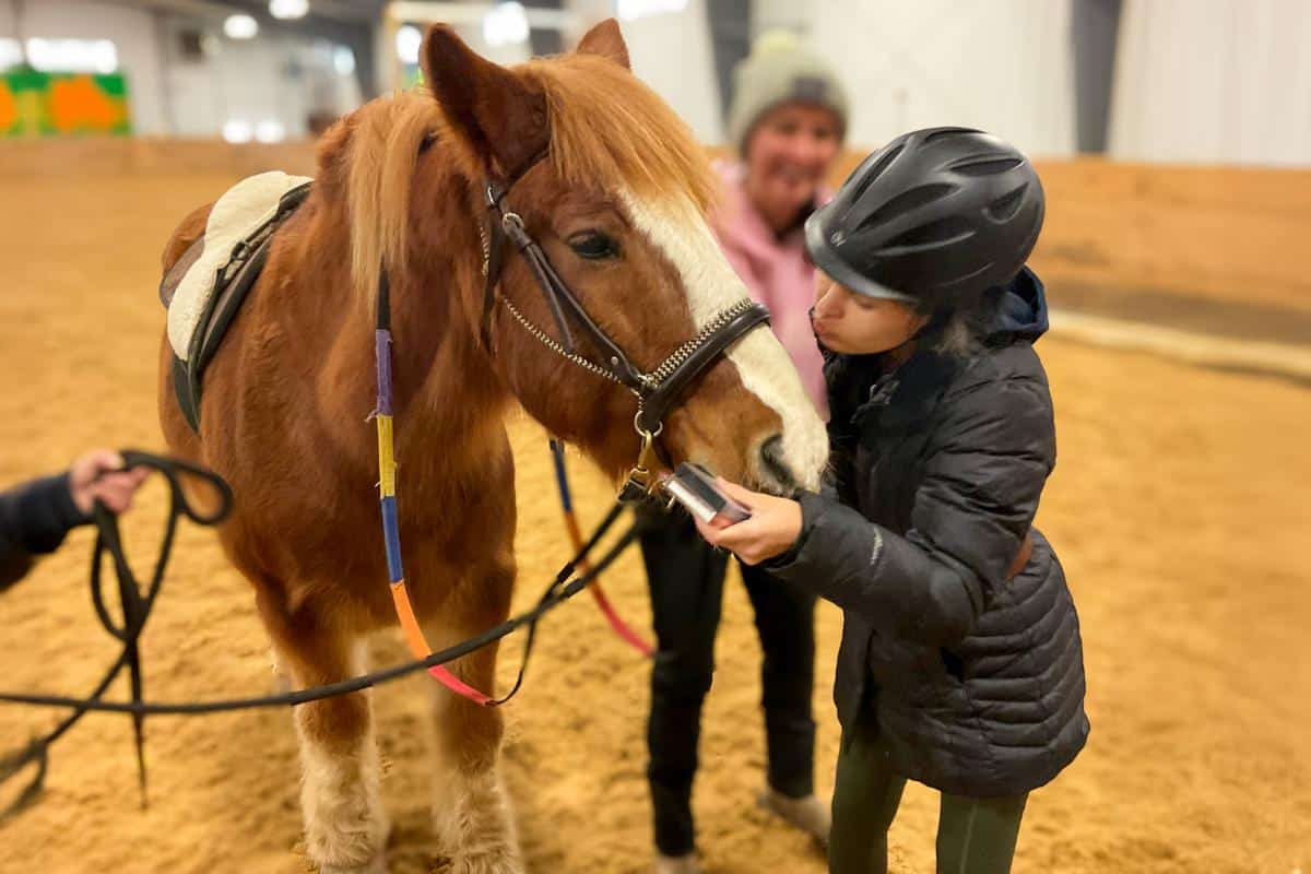Rider Leah giving adaptive riding horse Harry a kiss on the nose