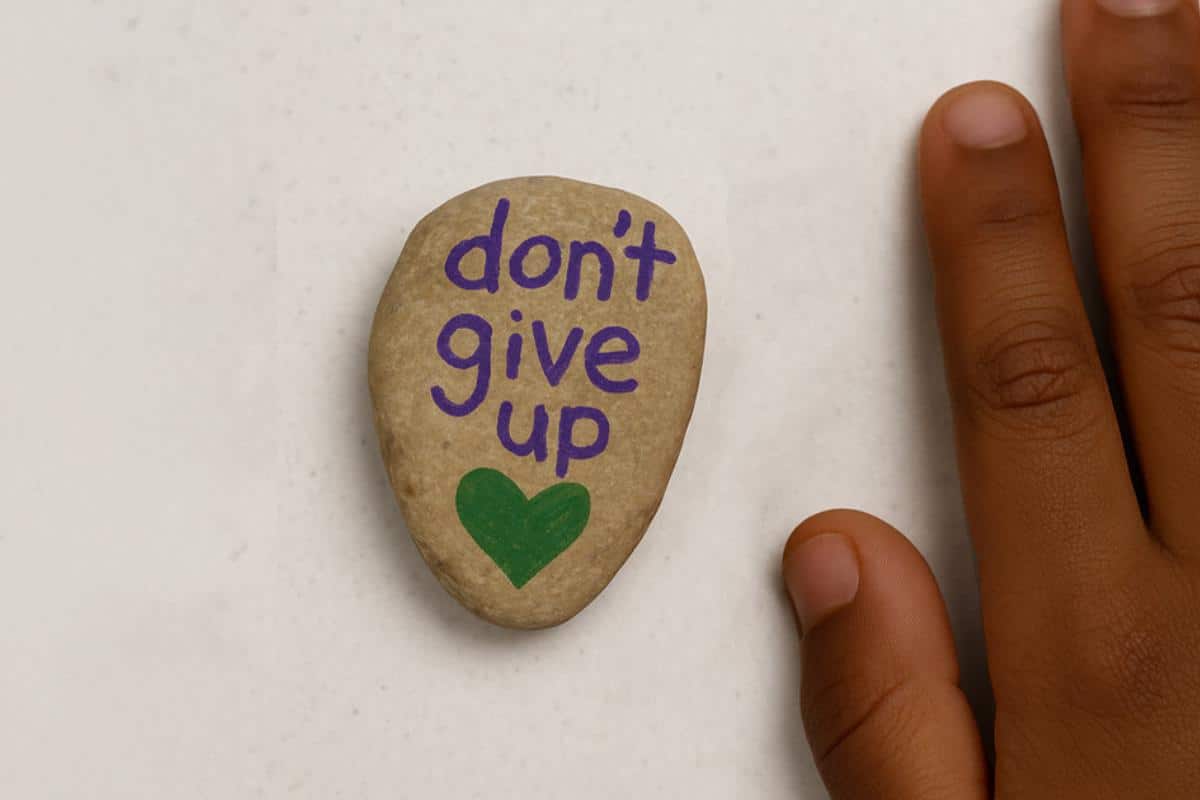 A rock with purple handwritten text that says "don't give up"
